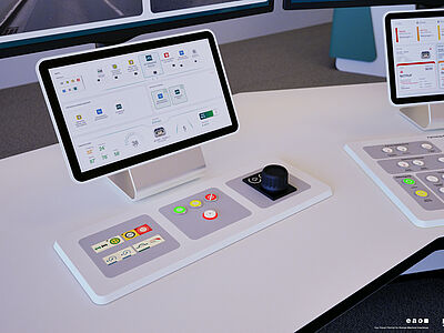 Eine Konsole mit verschiedenen bunten Knöpfen sowie ein Monitor auf einem Schreibtisch