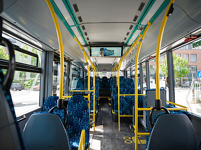 Innenraum eines Wasserstoffbusses mit gelben Haltegriffen und blau gemusterten Sitzen