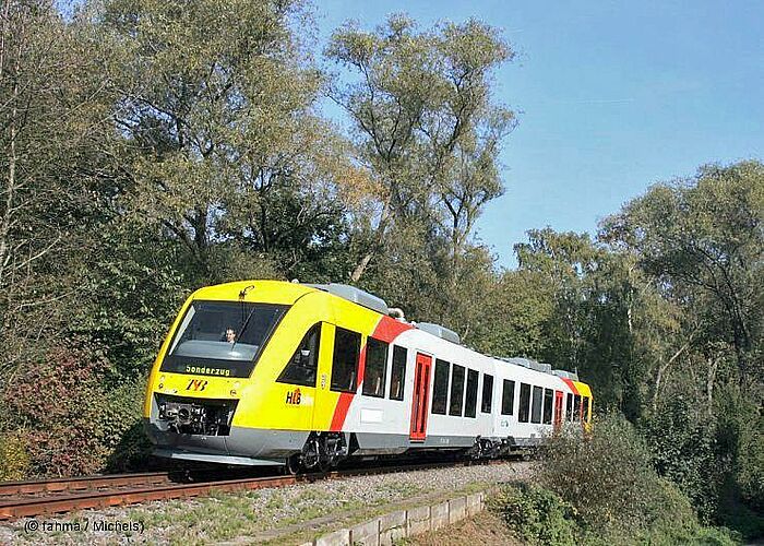 Vergrößerte Ansicht: Die Taunusbahn fährt auf einer Strecke durch Wald.