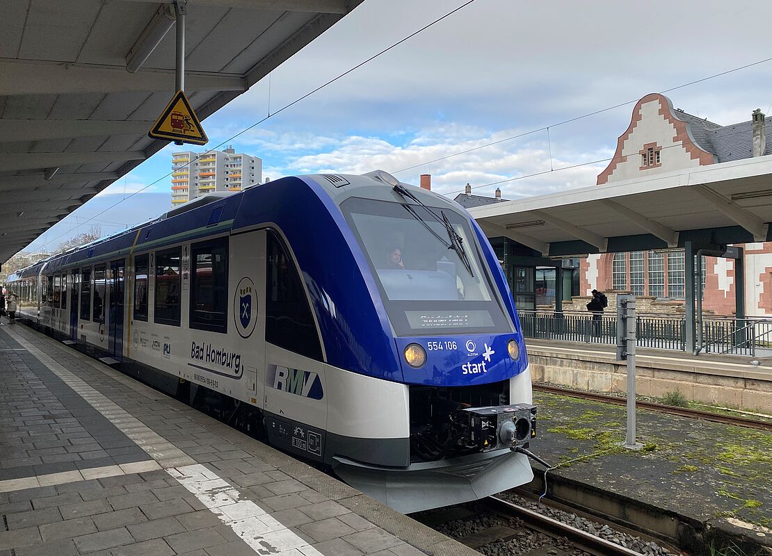 Blauweißer Zug steht auf einem Gleis im Bahnhof